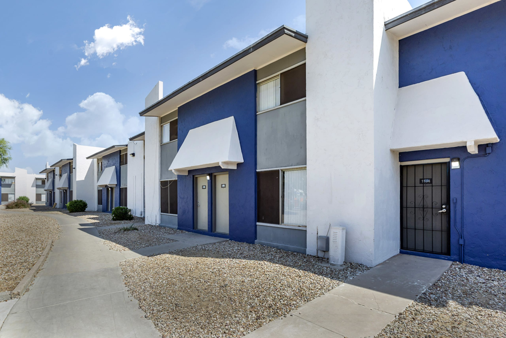 a row of blue and white apartment buildings with a sidewalk