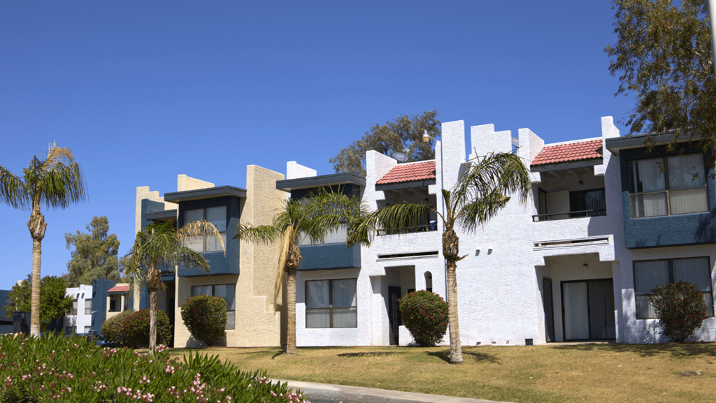 a row of white and blue apartment buildings with palm trees in front of them