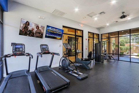 the gym has cardio equipment and glass doors to the pool
