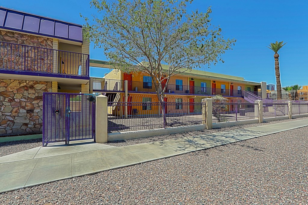 A building with a purple fence and a tree in front.