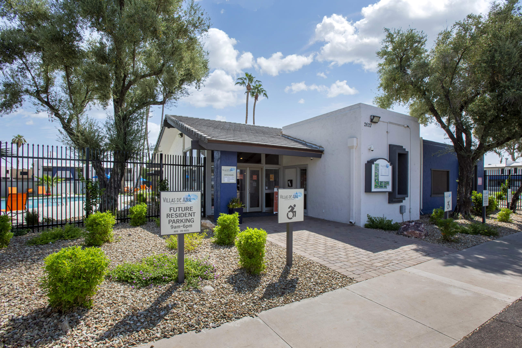 a white building with a gate and a sign in front of it