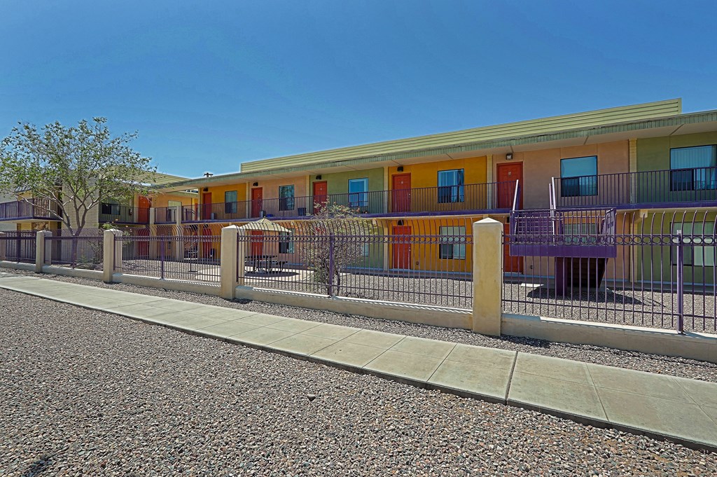 A row of colorful buildings with a fence in front.