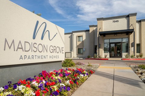 The entrance to Madison Grove Apartment Homes is shown with a sign and a flower bed.