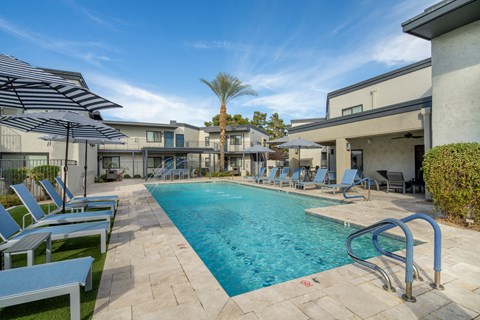 A swimming pool surrounded by lounge chairs and umbrellas.