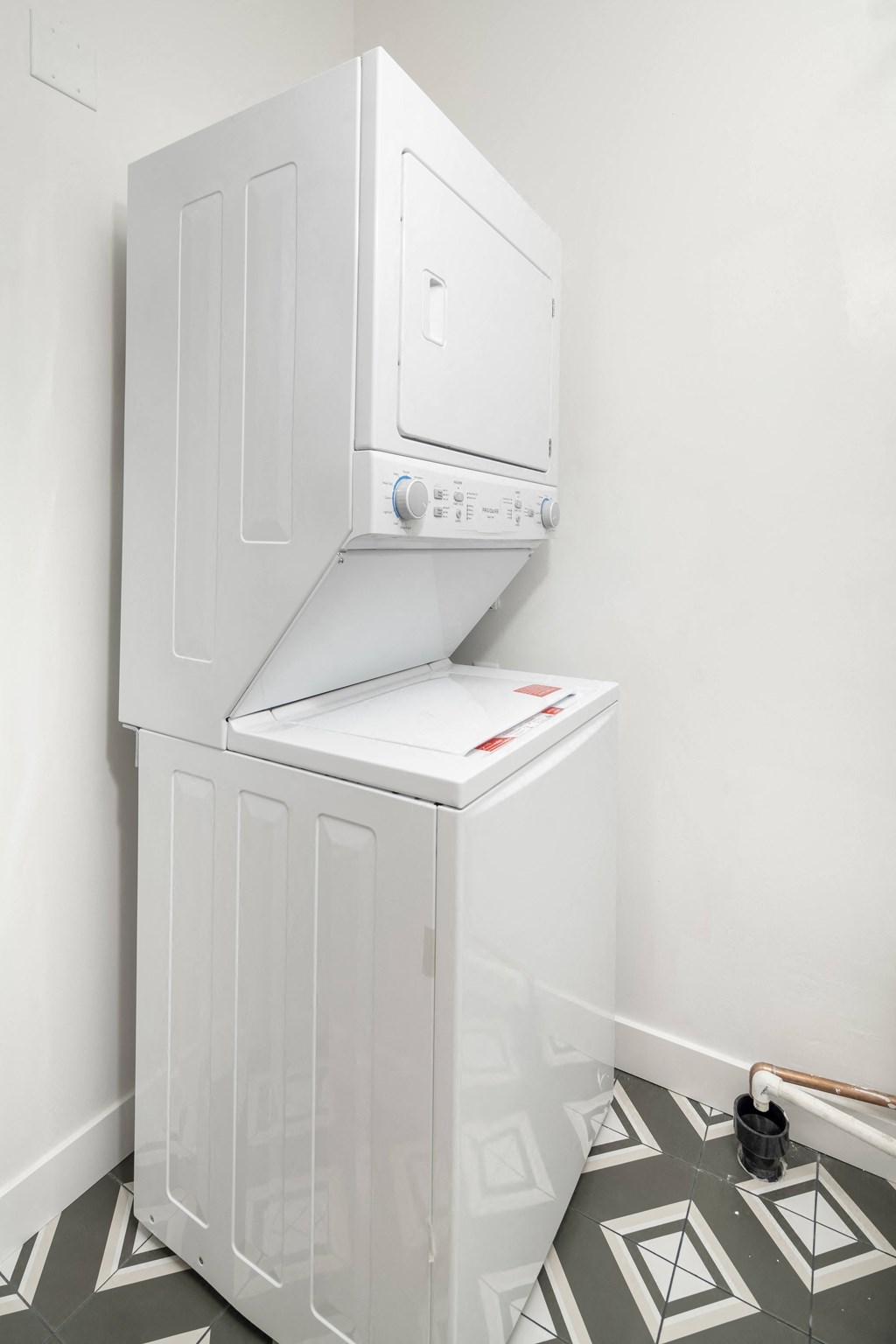 a white washer and dryer in a white room with a tiled floor