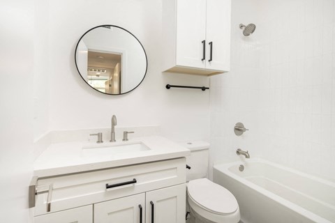a white bathroom with a white sink and toilet and a bath tub