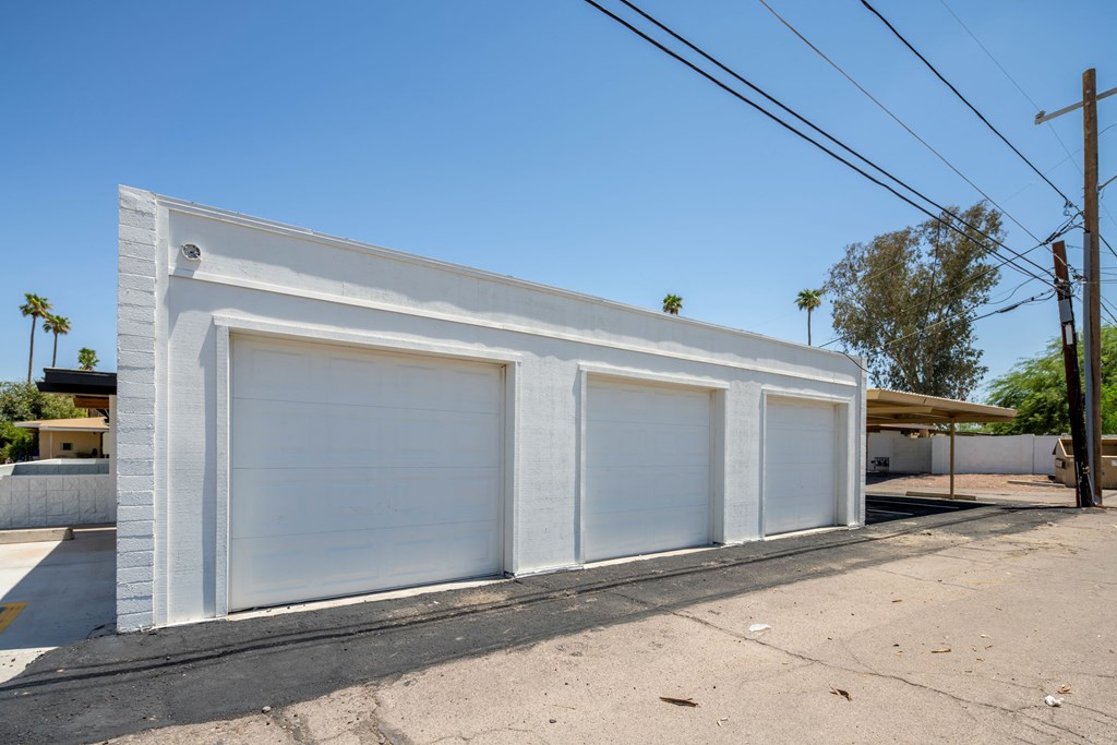 a small white building with three garages on the side of it