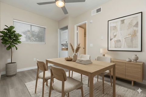 A dining room with a table, chairs, and a plant.