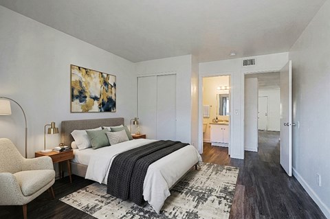 A bedroom with a large bed and a chair.