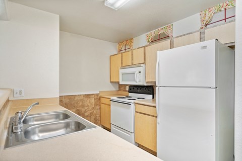 a kitchen with white appliances and a sink and a refrigerator