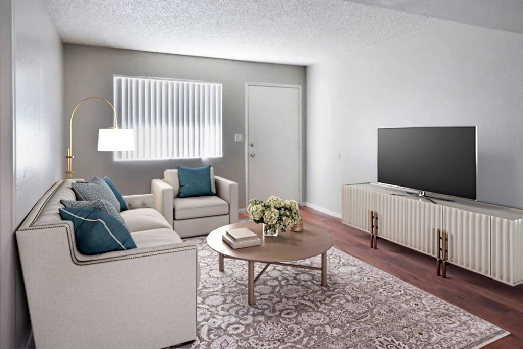 A living room with a white couch, a coffee table, and a flat screen TV.