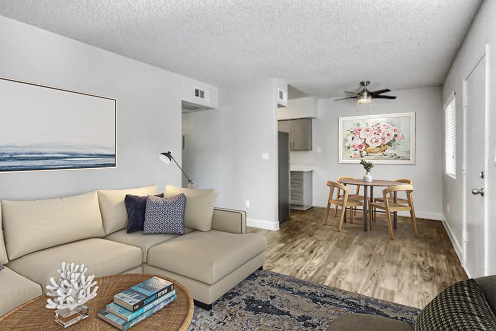 A living room with a beige couch, a coffee table, a ceiling fan, and a painting on the wall.