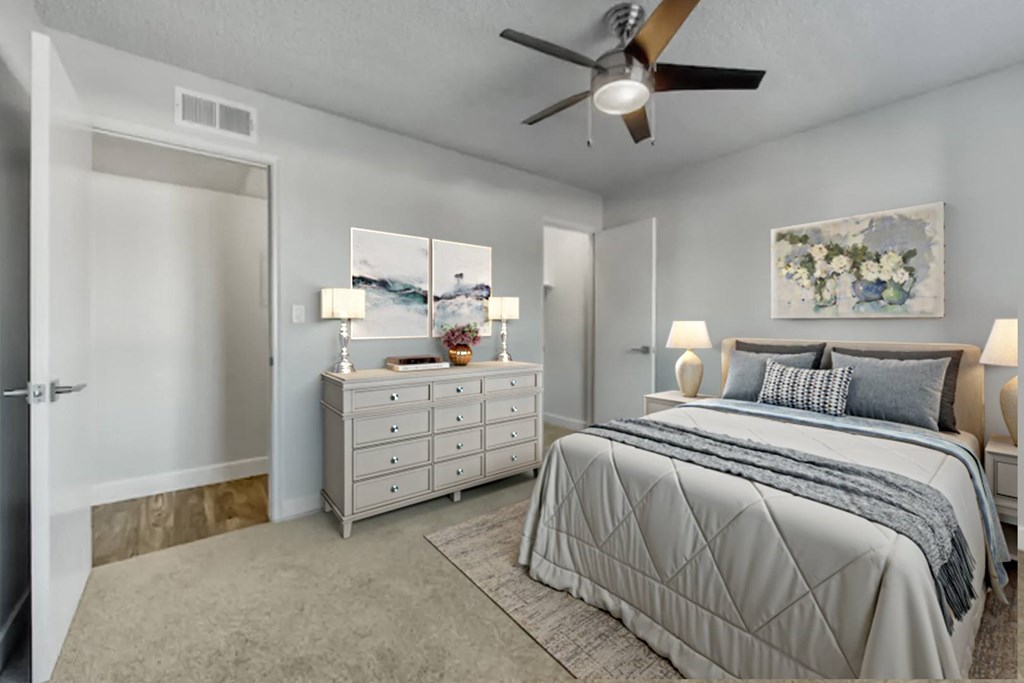 A bedroom with a large bed, a dresser, and a ceiling fan.