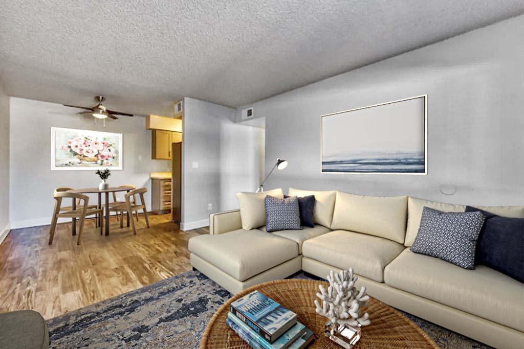 A living room with a beige couch, a coffee table, and a painting on the wall.