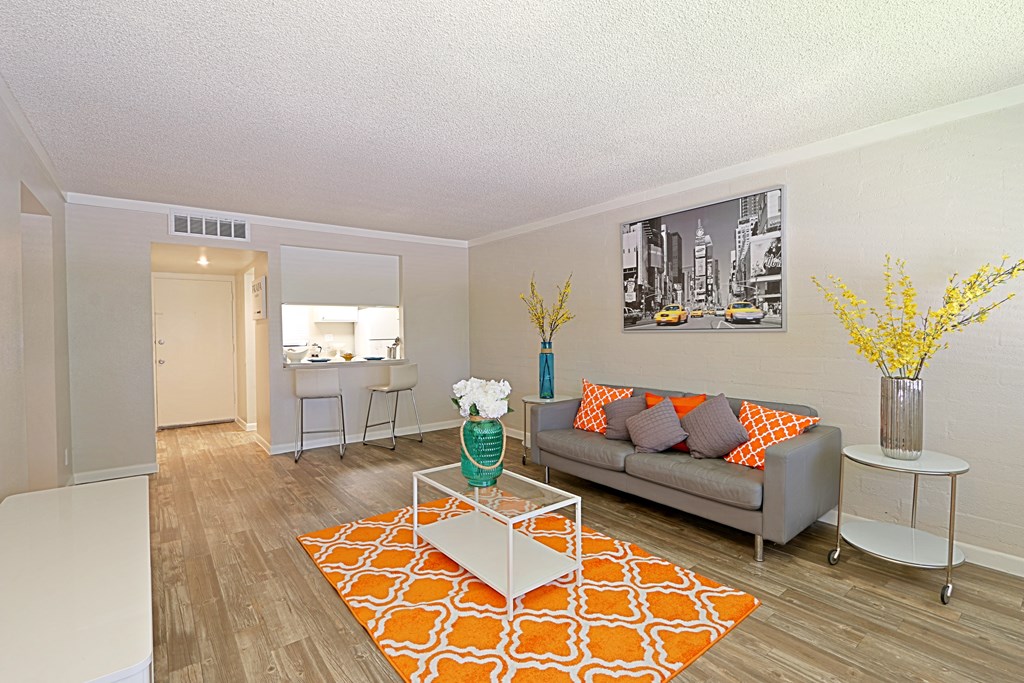 a living area with a couch coffee table and a kitchen in the background
