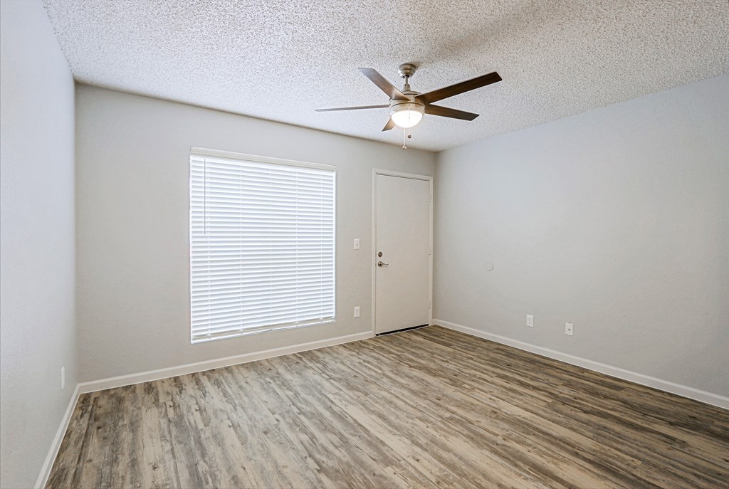 an empty living room with a ceiling fan and a window