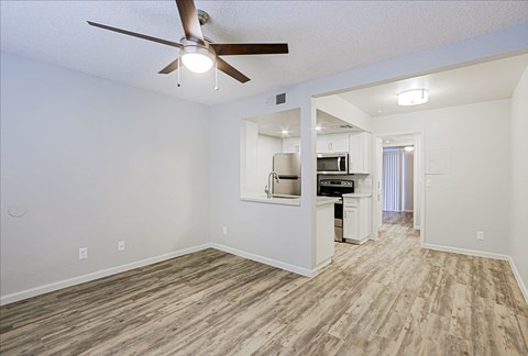 A room with a ceiling fan and a kitchenette.