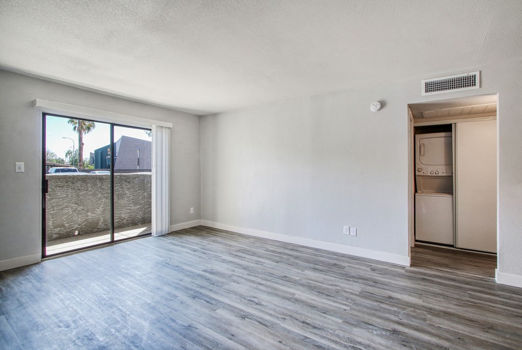 the living room of an apartment with wood flooring and a sliding glass door
