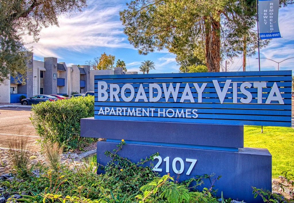 a blue sign that says broadway visa apartment homes in front of a parking lot