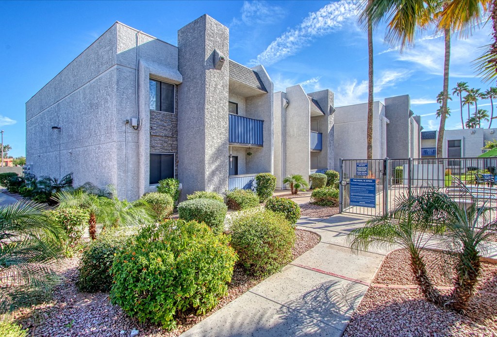 a building with palm trees and shrubs in front of it