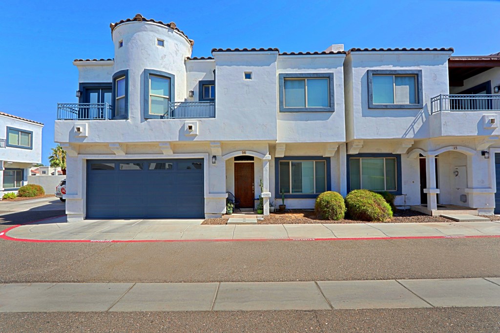 A white two story house with a balcony on the second floor.