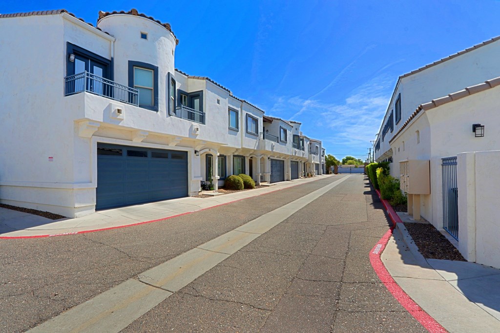 A row of white buildings with balconies and garage doors.