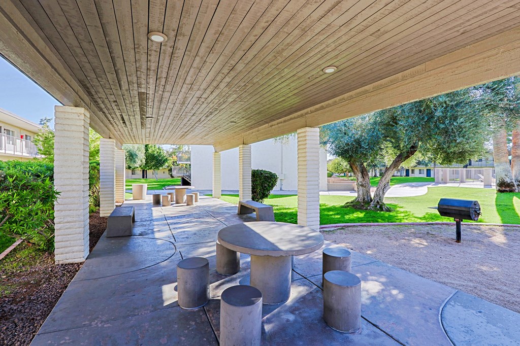 A concrete patio with a wooden roof and a mailbox.