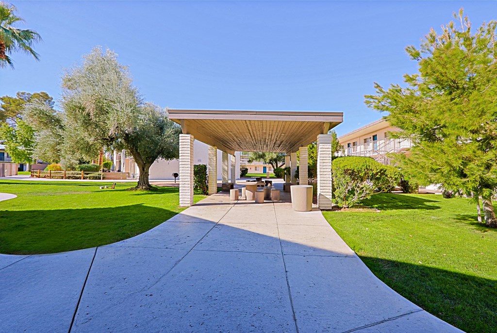 A pavement leads to a pavilion with a roof supported by four pillars.