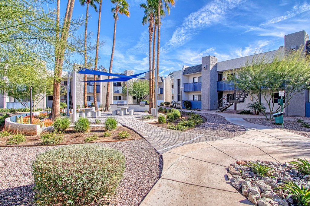 a courtyard with trees and a building with a blue canopy