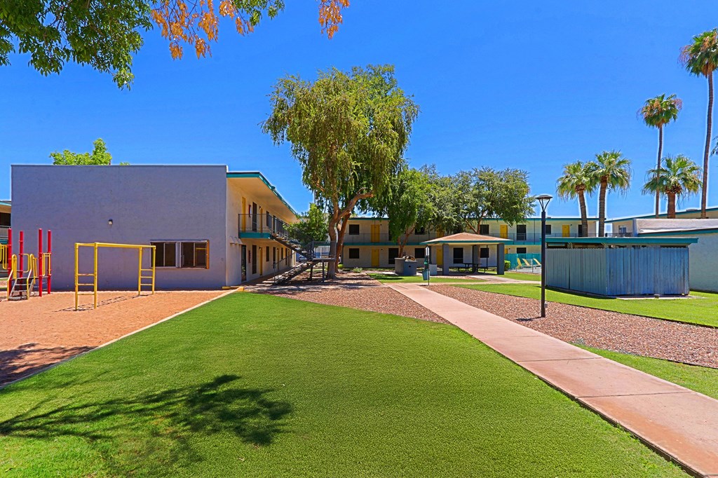 A playground area with a slide and a building in the background.