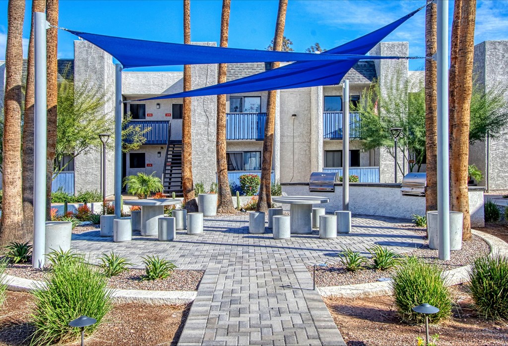 a courtyard with benches and umbrellas in front of an apartment building