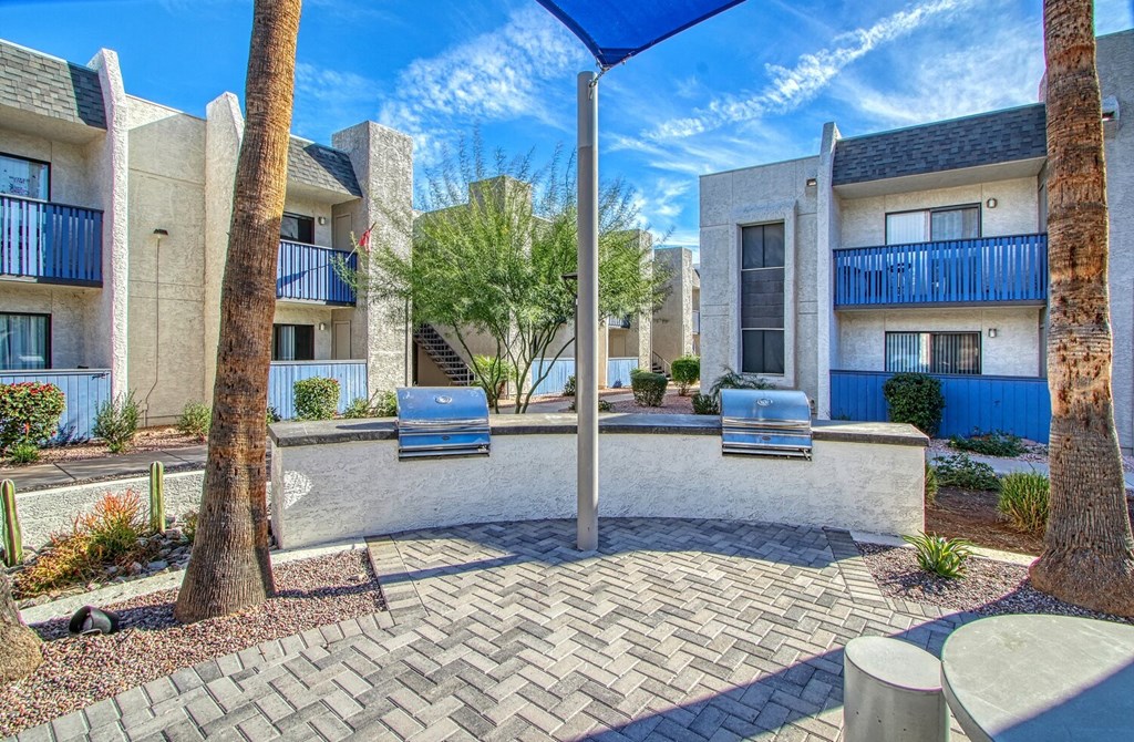 an outdoor patio with two chairs and trees in front of apartment buildings
