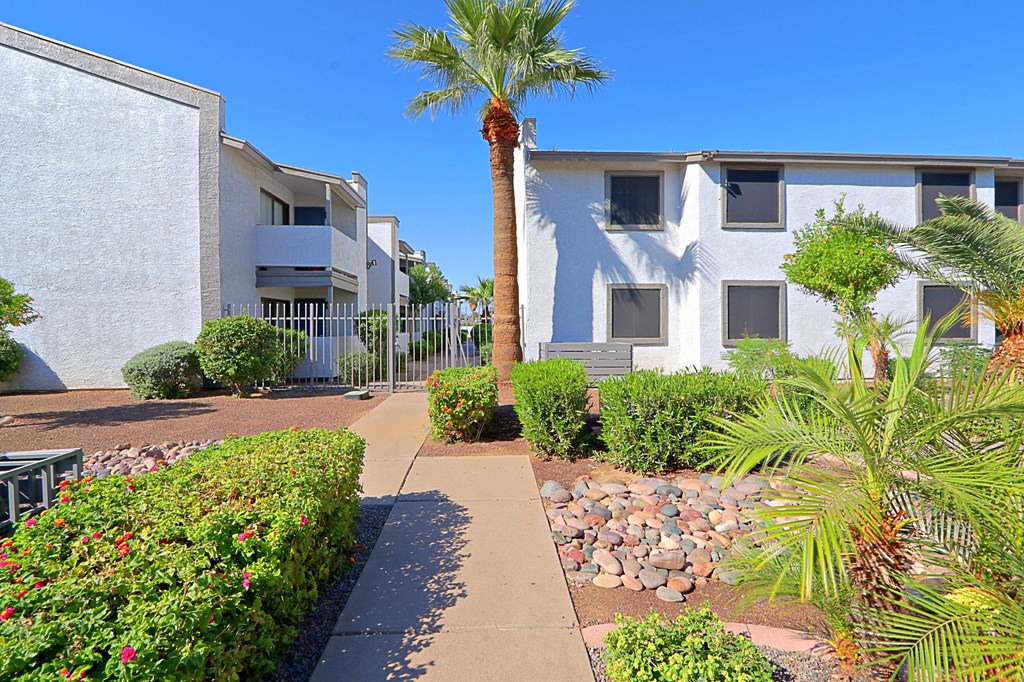 an apartment building with a walkway and palm trees in front of it