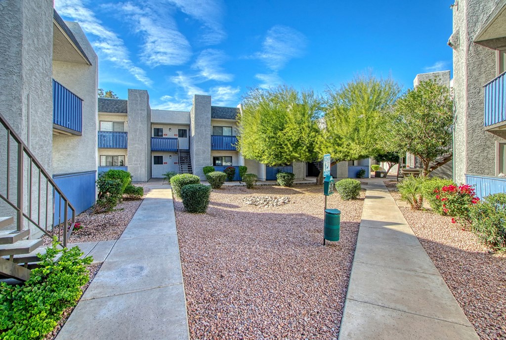 a courtyard between two apartment buildings with trees and plants