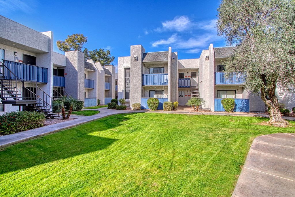 an exterior view of an apartment building with grass and trees