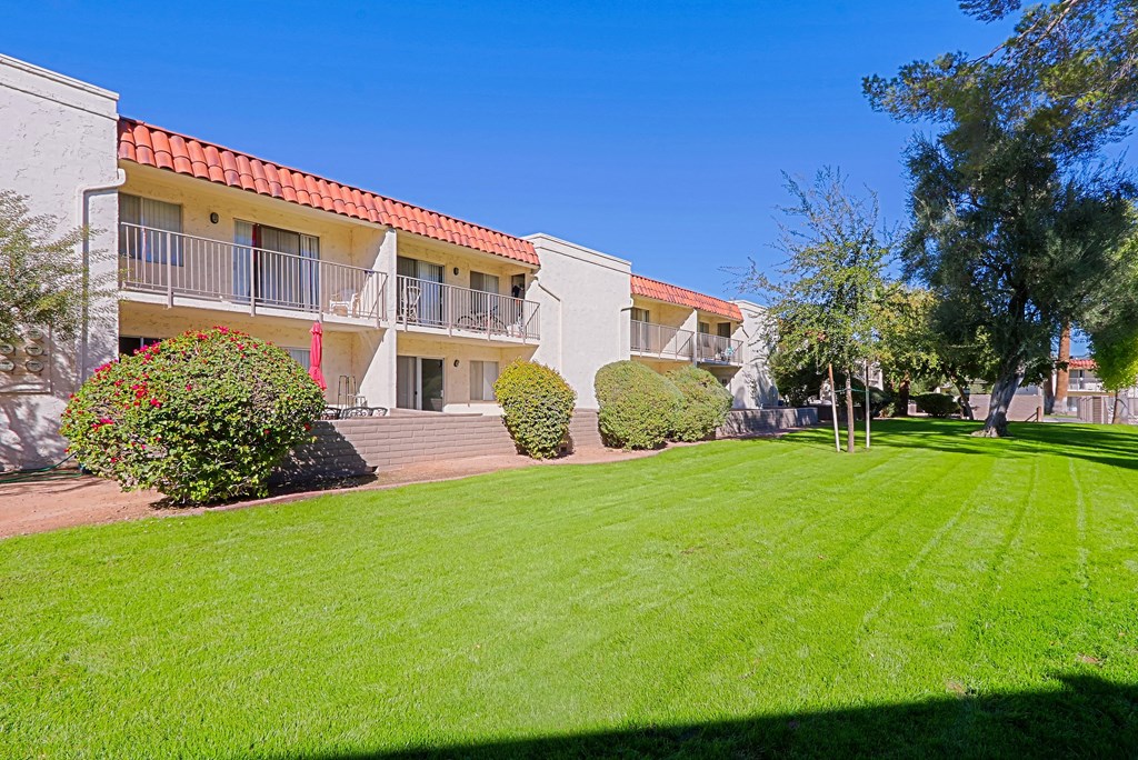 A building with a red roof and a green lawn in front.