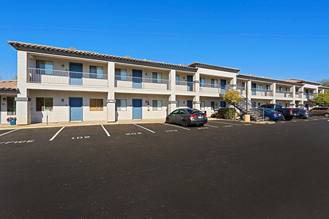 an apartment building with a parking lot and cars in front of it