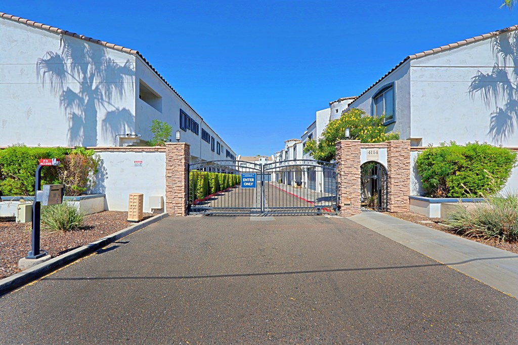 A gated entrance to a building with a wall mural of a palm tree.