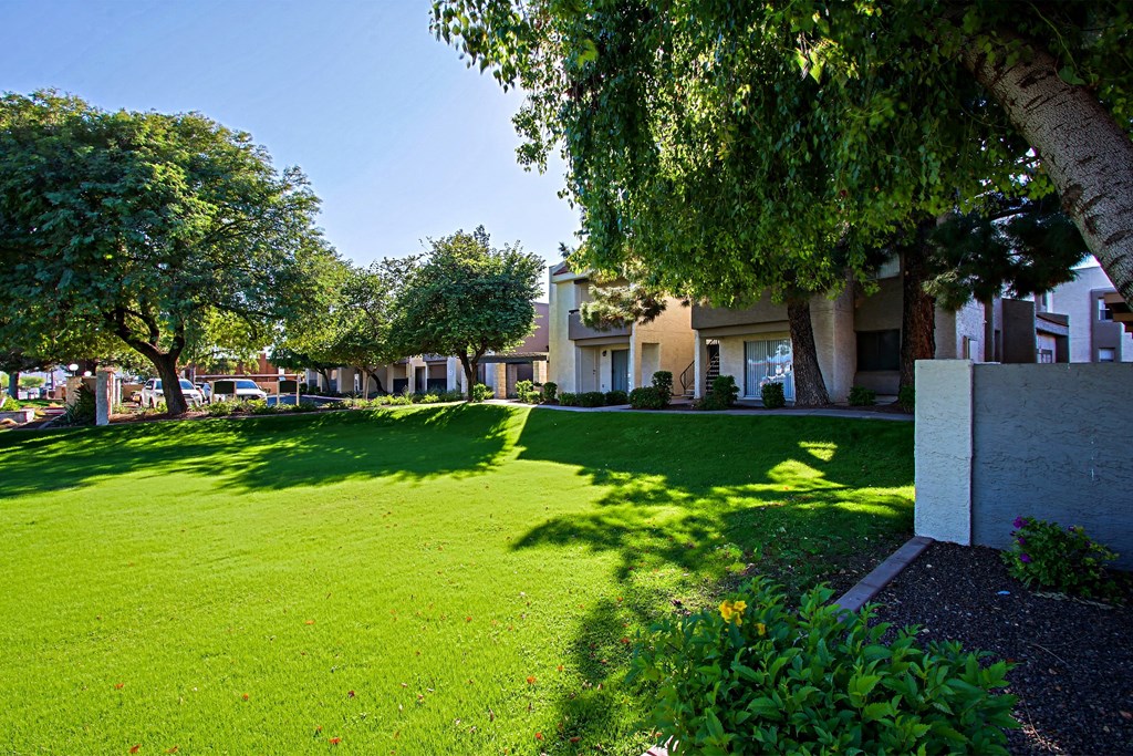 a green lawn in front of a building with trees