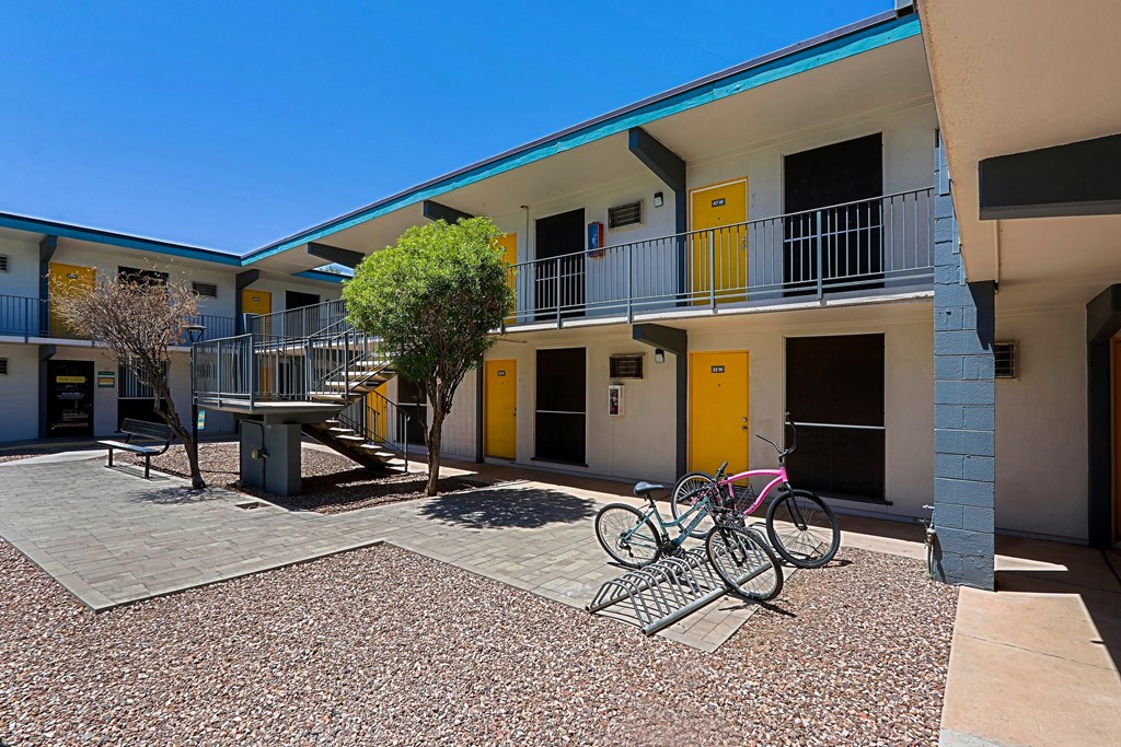 A bicycle is parked on a gravel area in front of a building with yellow doors.