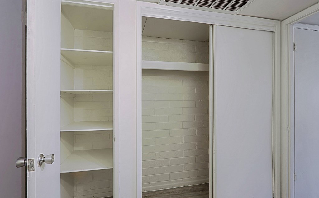 A white pantry with open doors and shelves.