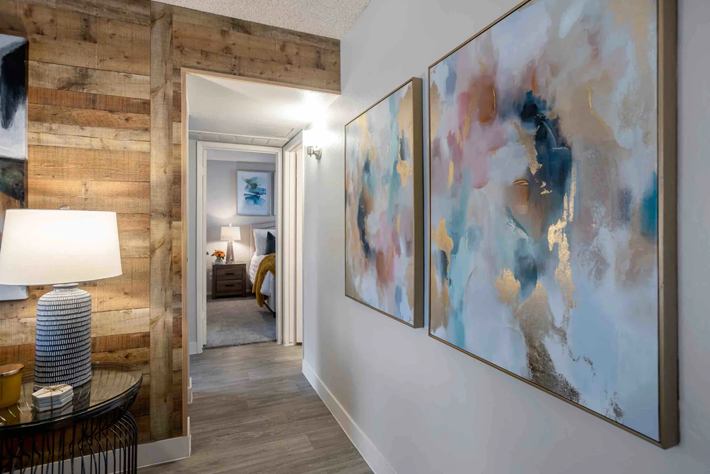 a hallway with paintings on the wall and a door to a bedroom