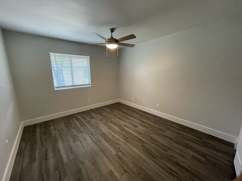 an empty bedroom with hardwood floors and a ceiling fan