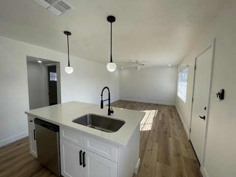 a kitchen and living room with white cabinets and a sink