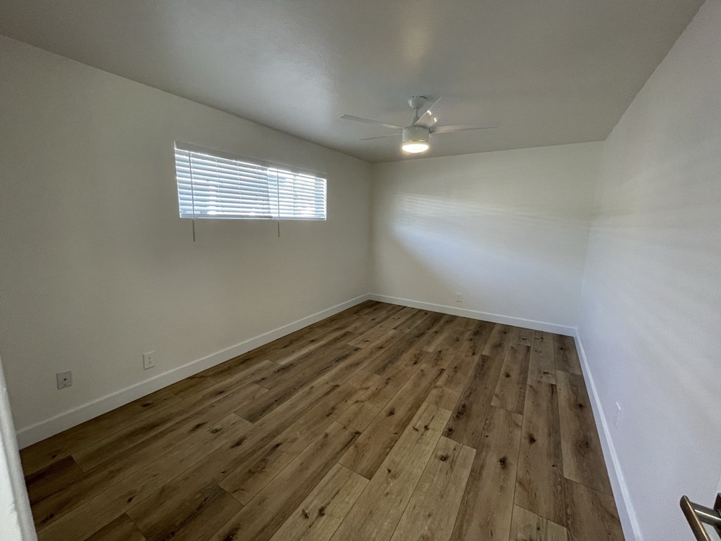 an empty living room with wood flooring and a ceiling fan