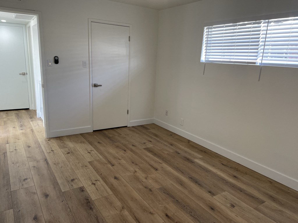 a bedroom with wooden floors and white walls and a door