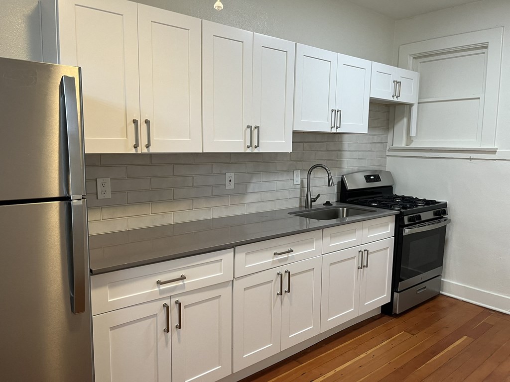 a kitchen with white cabinets and a sink and a refrigerator