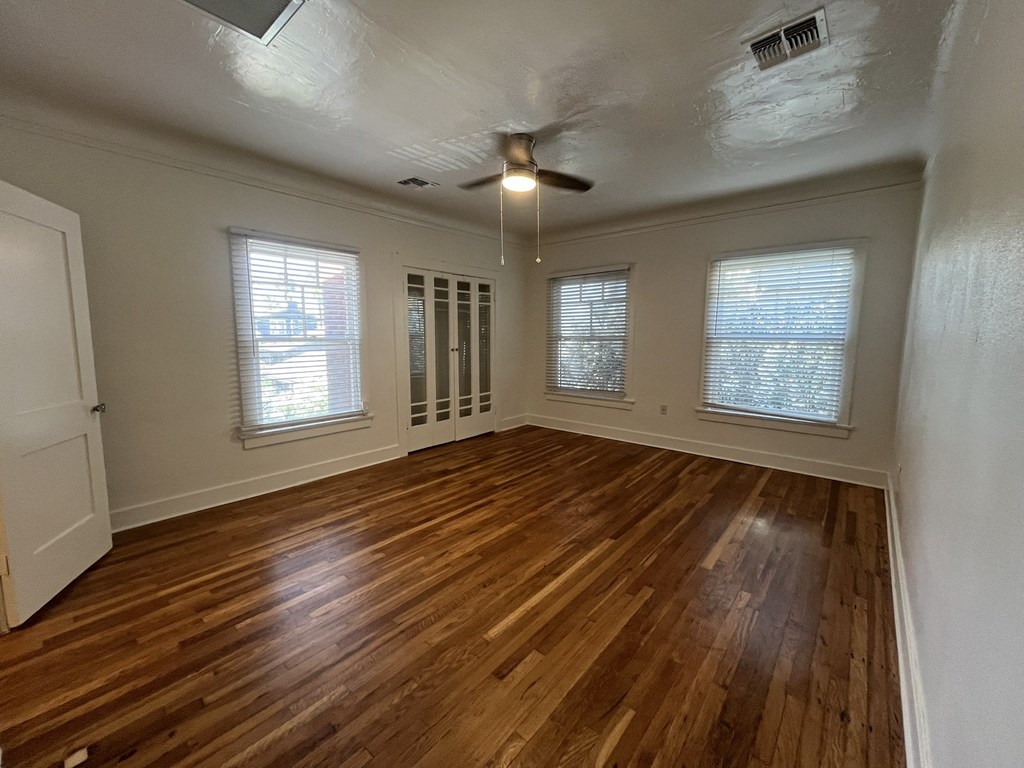 an empty living room with wood floors and a ceiling fan