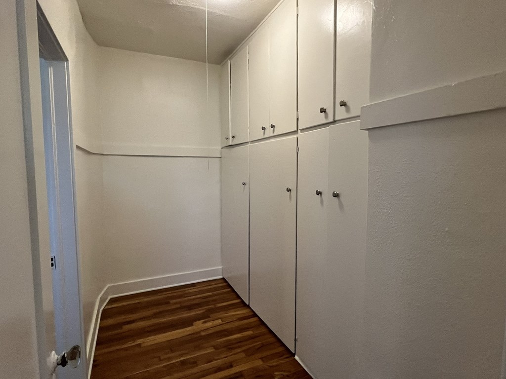 a bedroom with white cabinets and a wood floor
