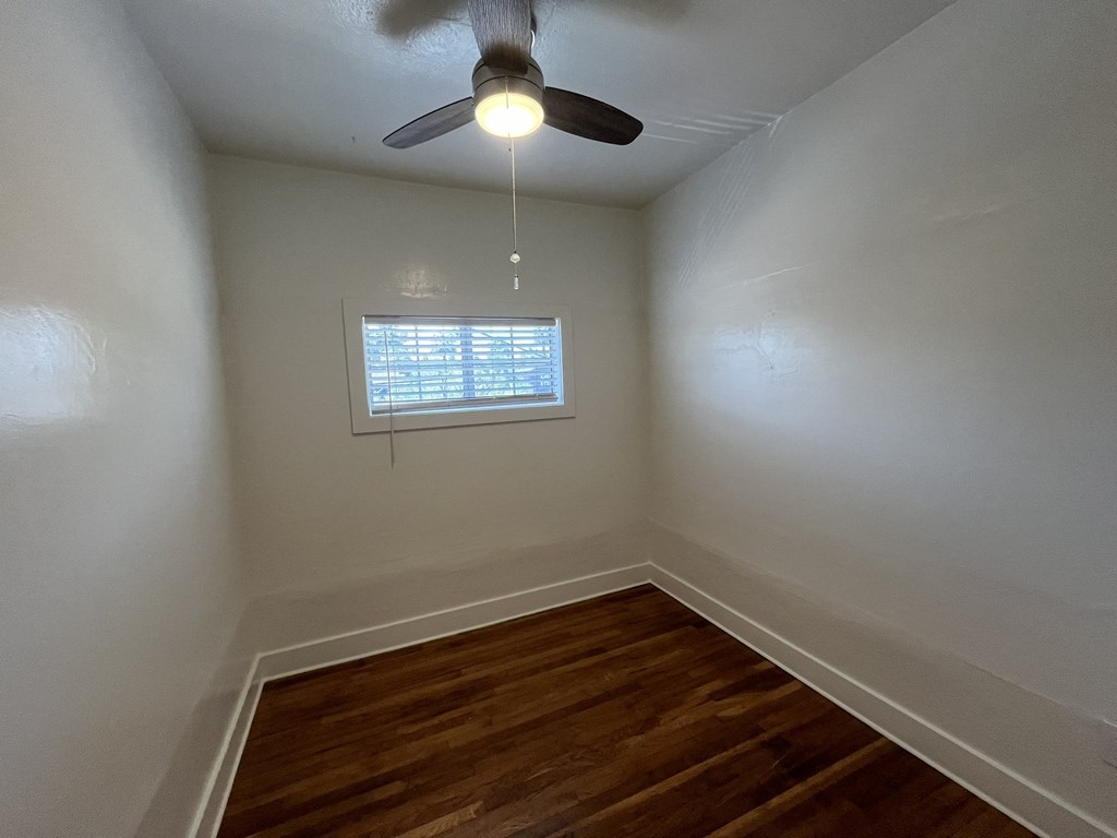 an empty room with a ceiling fan and a window